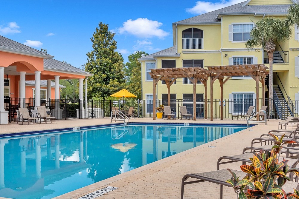 Pool with chaise lounges and pergola at Bermuda Estates Apartments in Ormond Beach, FL