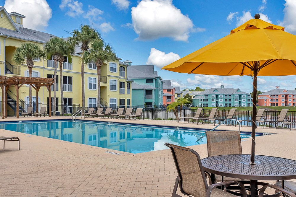 tables and umbrellas with seating at Bermuda Estates Apartments in Ormond Beach, FL