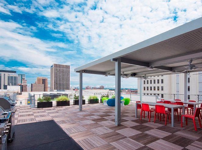 a rooftop patio with tables and chairs and a view of the city