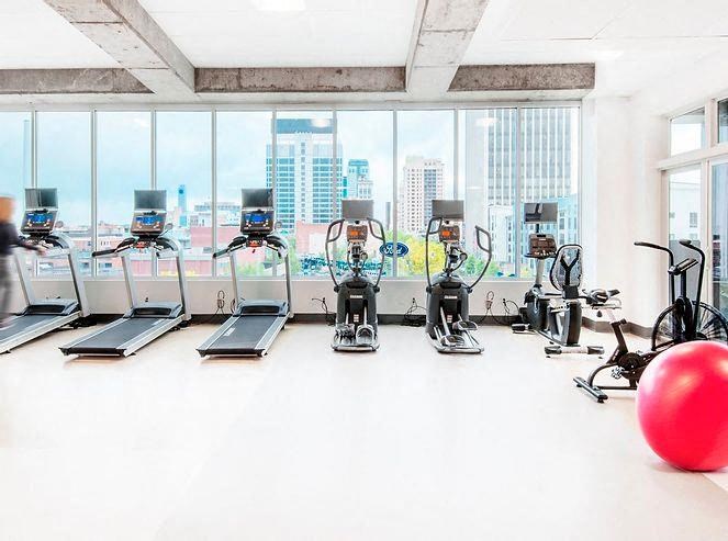 a gym with cardio machines and a large window