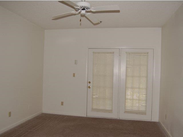 an empty living room with a ceiling fan and a door