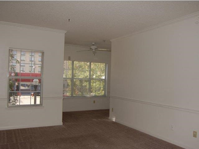 an empty living room with a window and a ceiling fan