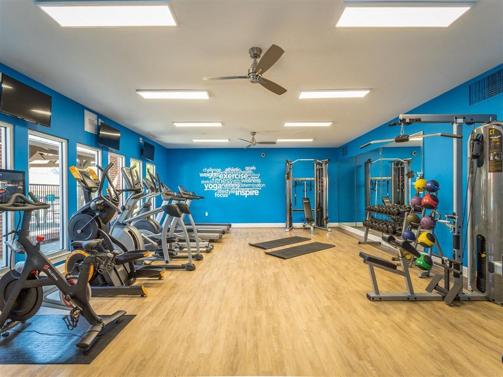 a gym with exercise equipment and a ceiling fan