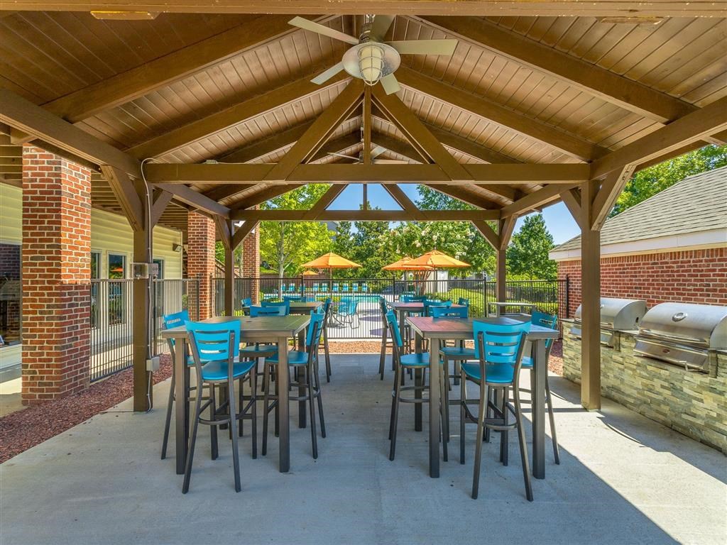 a patio with tables and chairs and a grill