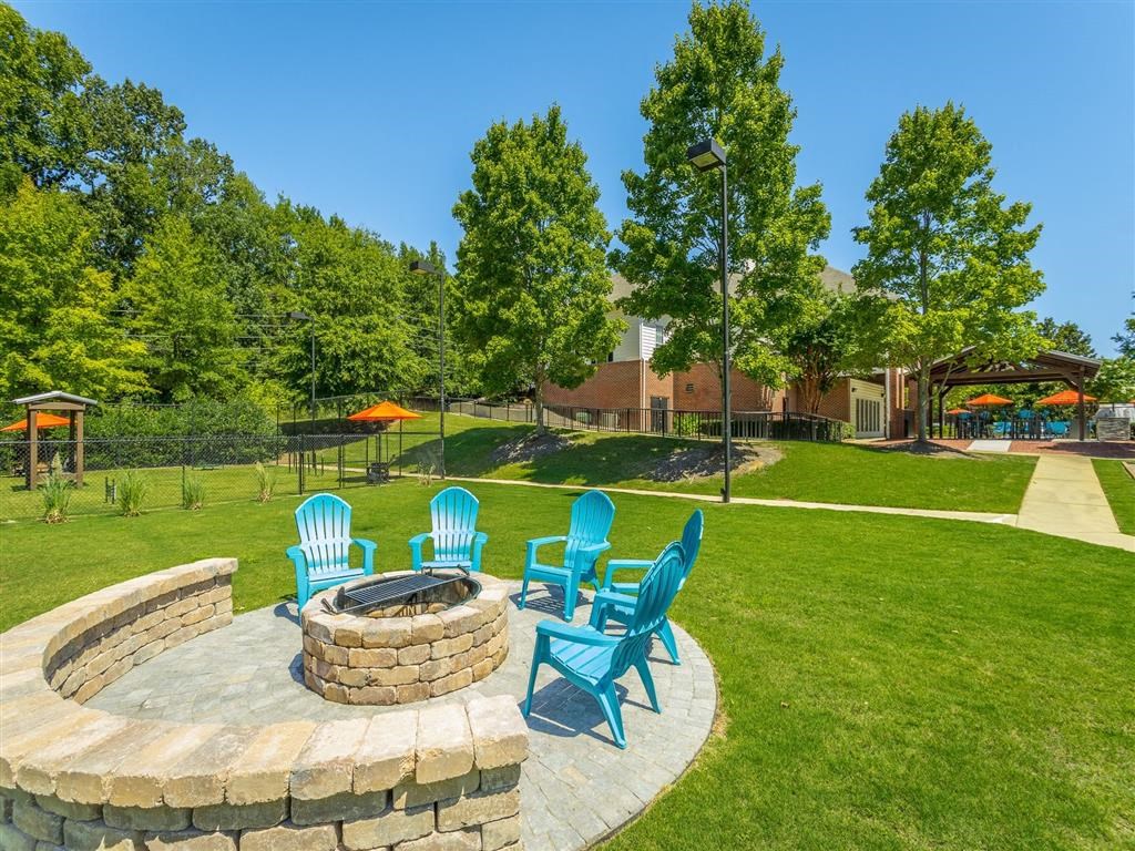 a patio with blue chairs and a fire pit