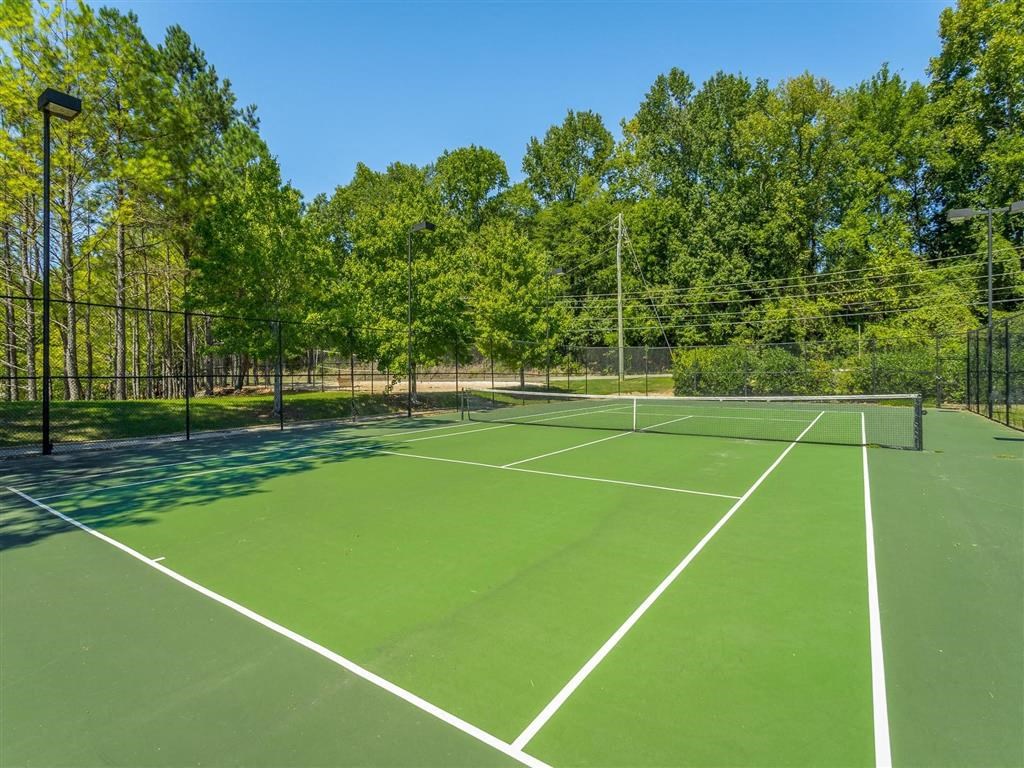 a tennis court with trees in the background on a clear day
