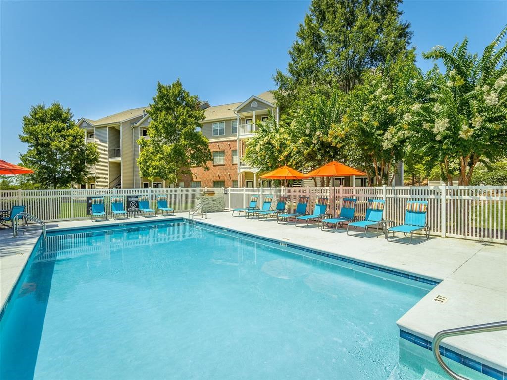 a swimming pool with blue chairs and orange umbrellas