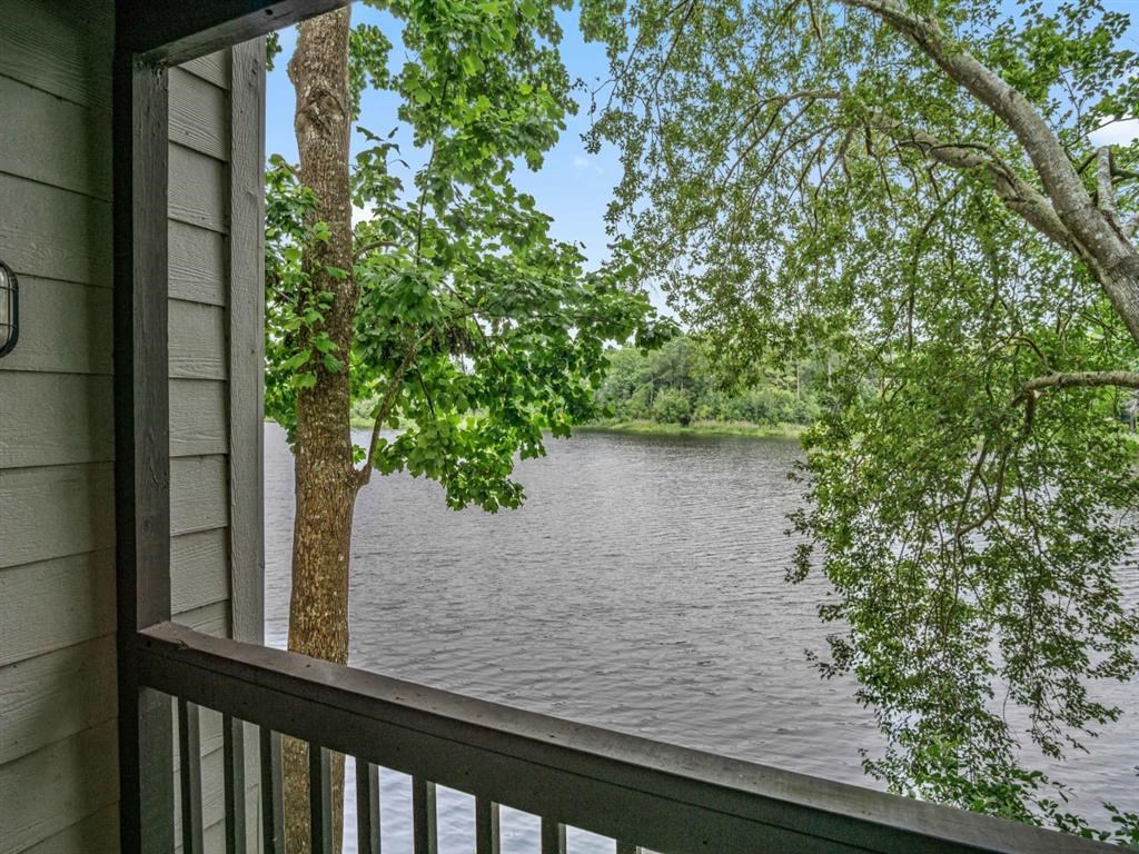 a view of a lake from a porch with a tree