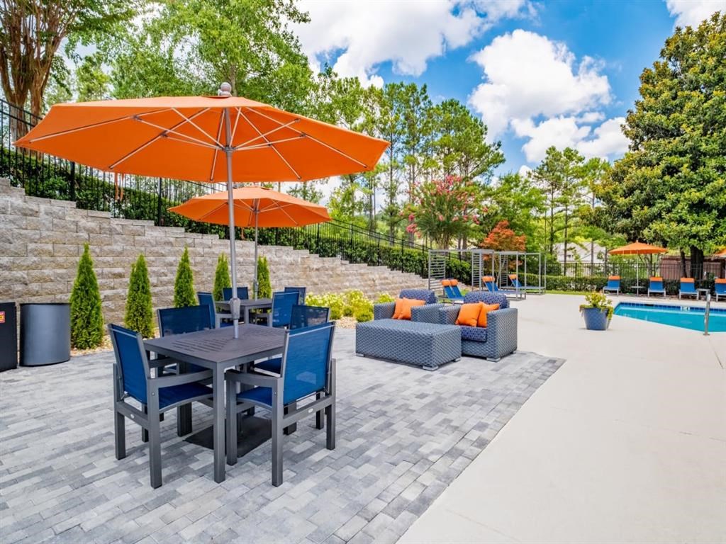 a patio with a table and chairs and an umbrella next to a swimming pool