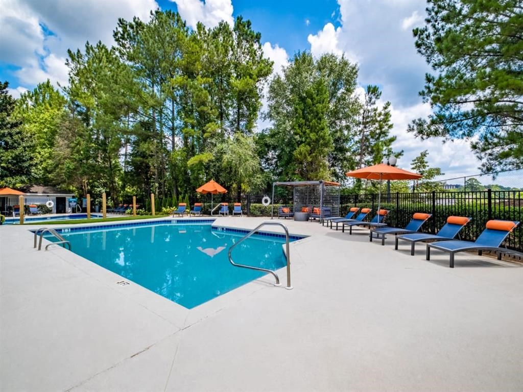 a swimming pool with chairs and umbrellas and trees