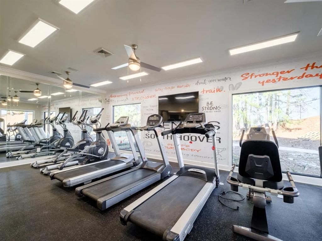a gym with cardio equipment and a wall of windows