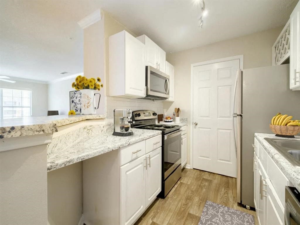 a kitchen with white cabinets and stainless steel appliances