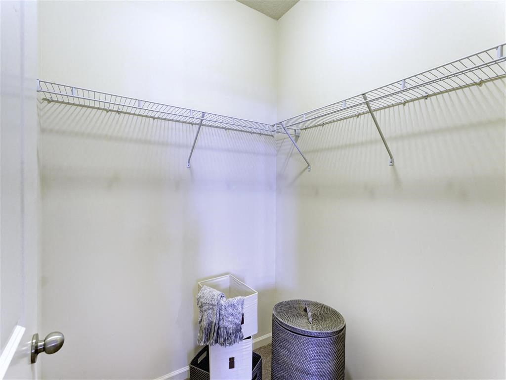 a walk in closet with a wire rack and a trash can