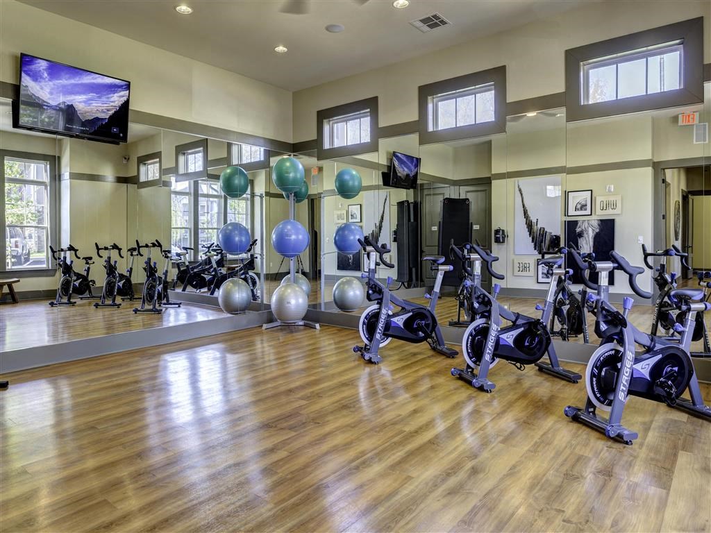 a gym with exercise equipment and weights on a wooden floor