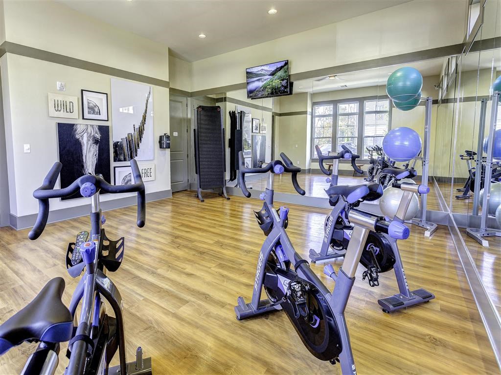 a gym with several exercise bikes and a tv