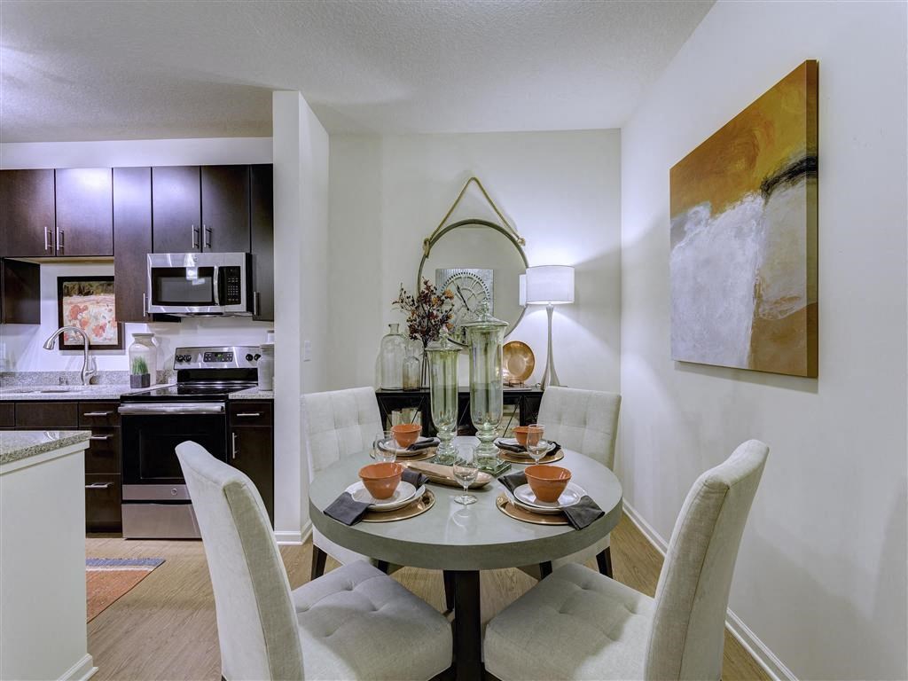 Louisville Kentucky Apartments - SpringHouse - Dining Room With Padded Chairs, Circular Table, Wooden Flooring, and a Wall Painting
