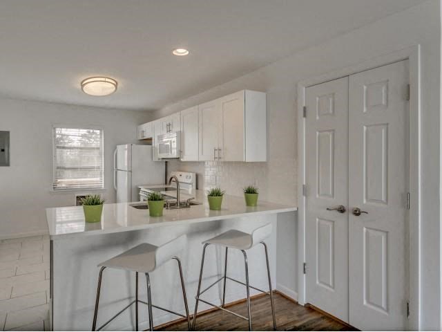 a white kitchen with bar stools and white cabinets
