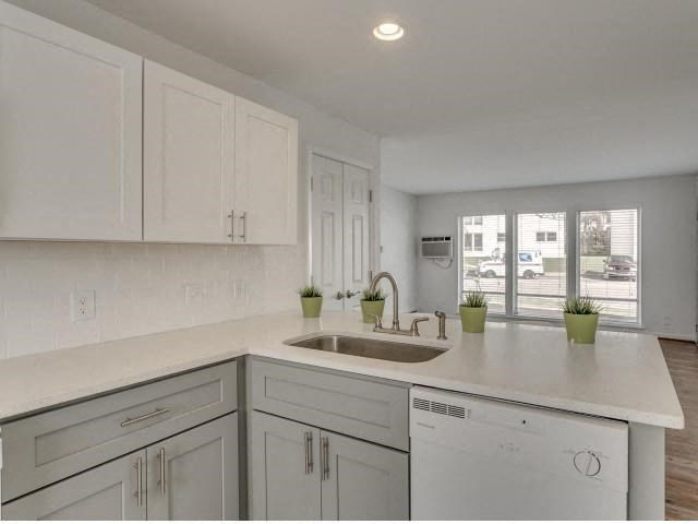 a white kitchen with a sink and white cabinets