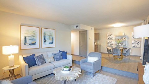 A living room with a grey couch, a white coffee table, and a painting on the wall.