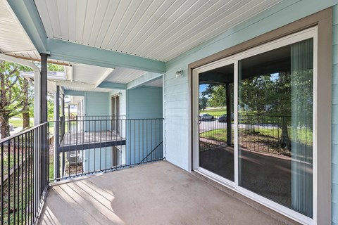A balcony with a black railing and a sliding glass door.