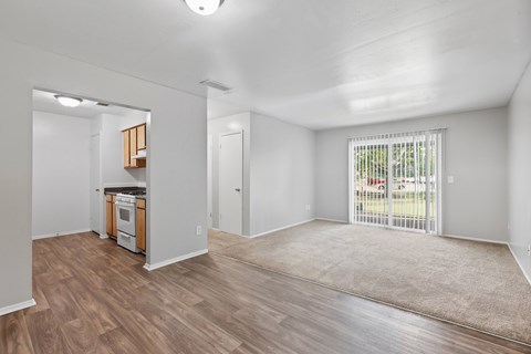A spacious living room with a kitchenette and sliding glass doors.