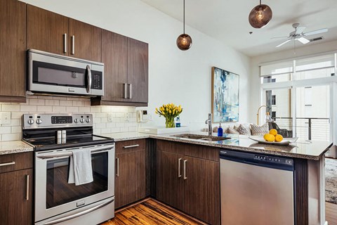 A modern kitchen with dark wood cabinets and stainless steel appliances.