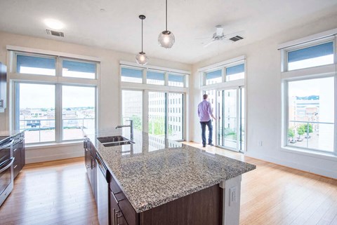 a kitchen with a granite counter top and a man walking out of a window