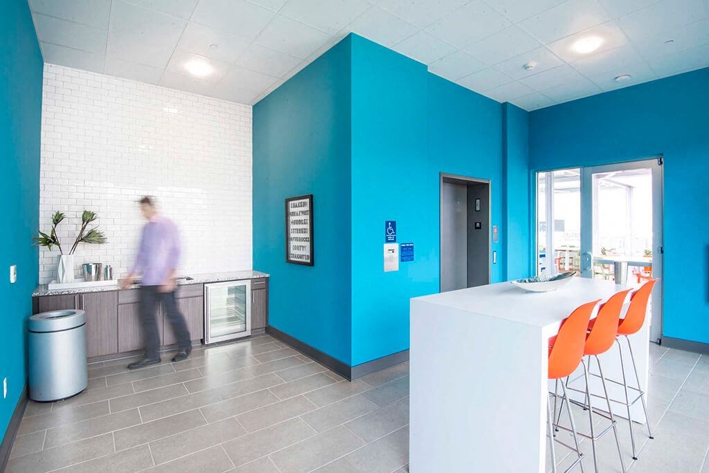 a man walking through a lobby with a blue wall