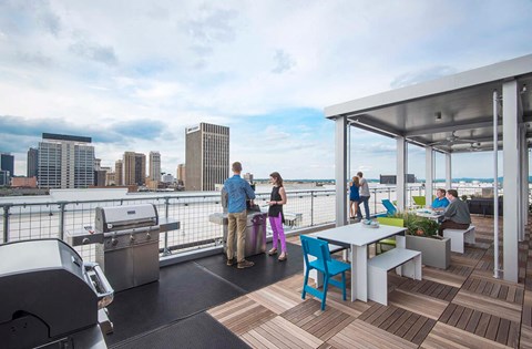 a rooftop deck with tables and chairs and a city in the background
