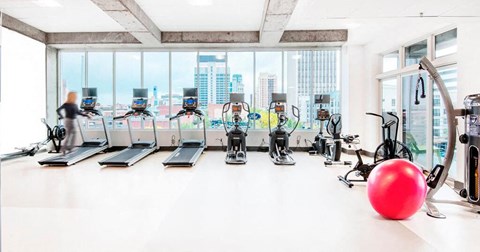 a large gym with cardio machines and a red ball