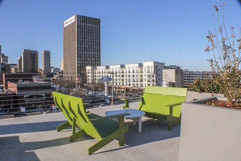 a patio with green chairs and a table on a roof