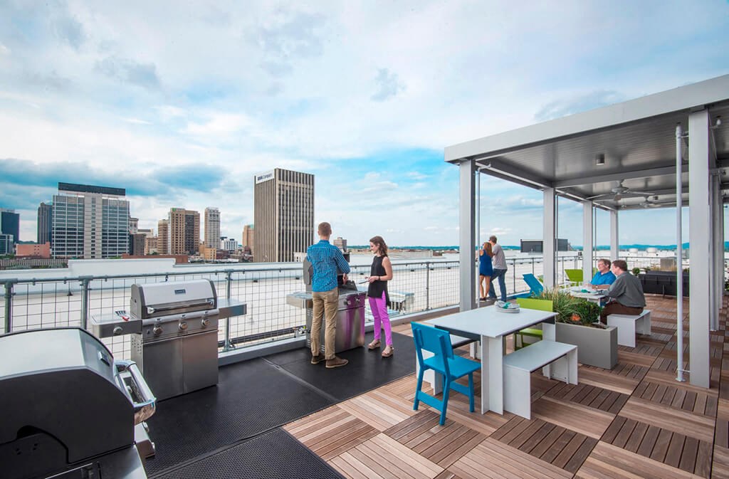 a rooftop deck with tables and chairs and a city in the background