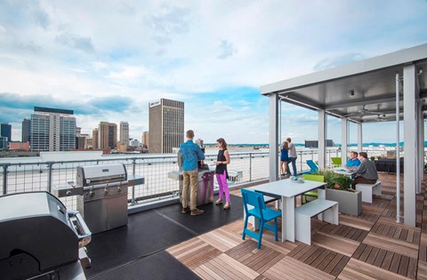 a rooftop deck with tables and chairs and a city in the background