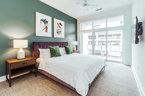 Bedroom with green accent wall and large windows at Reserve on 3rd Apartments, Birmingham, AL