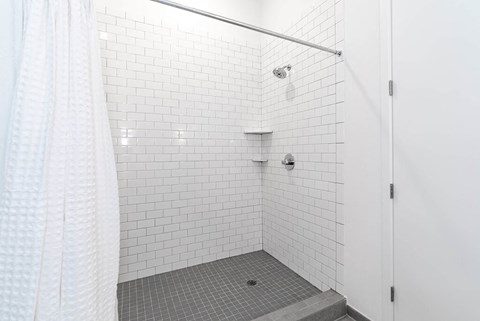 a white tiled shower in a bathroom with a shower curtain