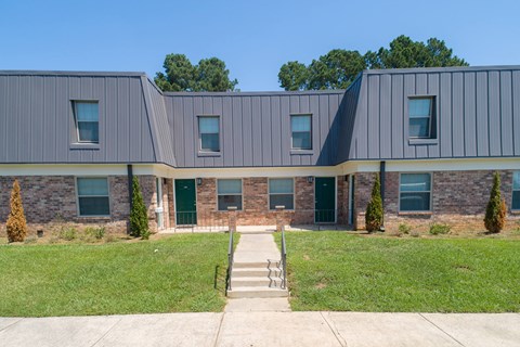 the front of a building with green doors and a sidewalk
