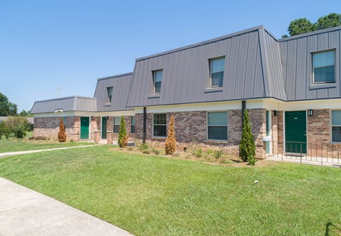 the front of a building with green doors and a lawn