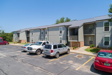 a parking lot with cars in front of an apartment building