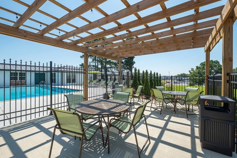a patio with tables and chairs next to a swimming pool