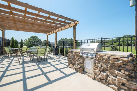 a patio with a barbecue grill and a table and chairs