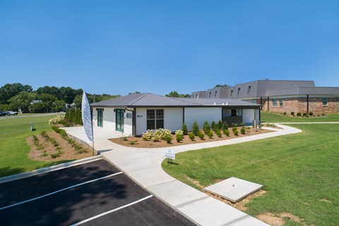 the front of a building with a sidewalk and grass