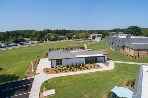 an aerial view of a building with a field and a parking lot