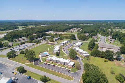 an aerial view of a city with houses and cars parked in a parking lot