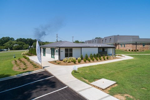 the front of a building with a lawn and a sidewalk