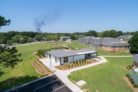 a view of a house from the air with a green field and trees