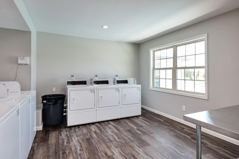 a laundry room with white washers and dryers and a window