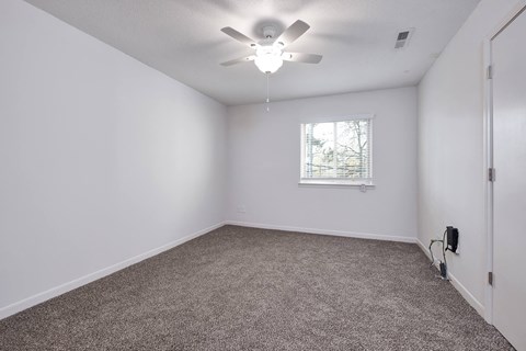 an empty room with white walls and a ceiling fan