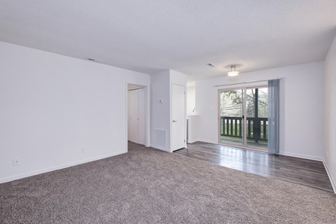 an empty living room with a sliding glass door to a balcony