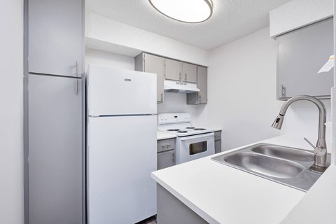 a white kitchen with a sink and refrigerator