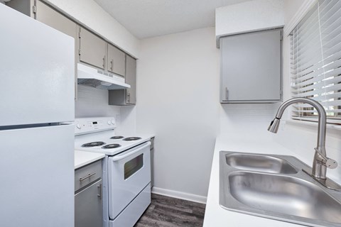 a white kitchen with white appliances and a stainless steel sink